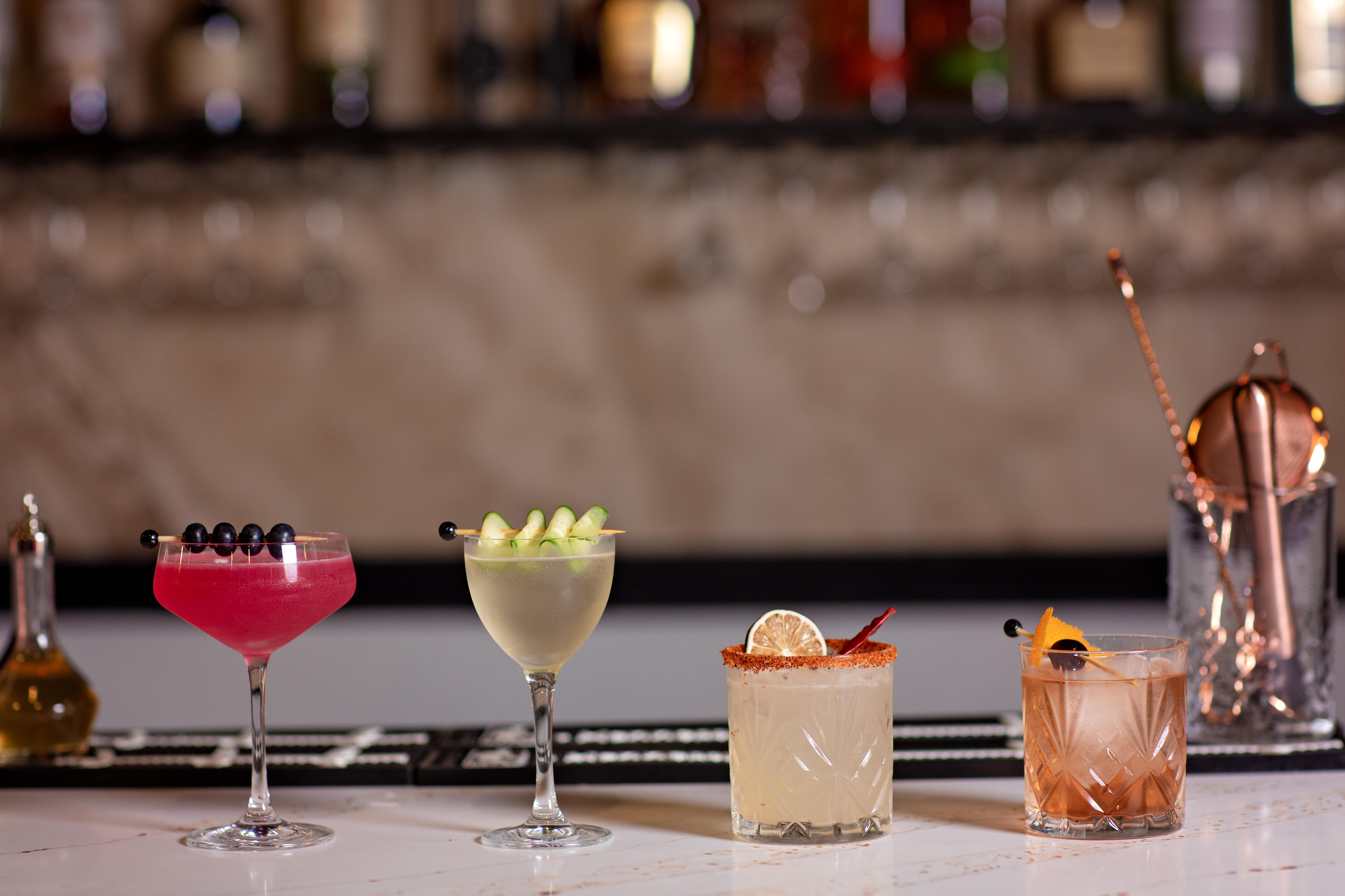 Four signature cocktails lined up along the bar