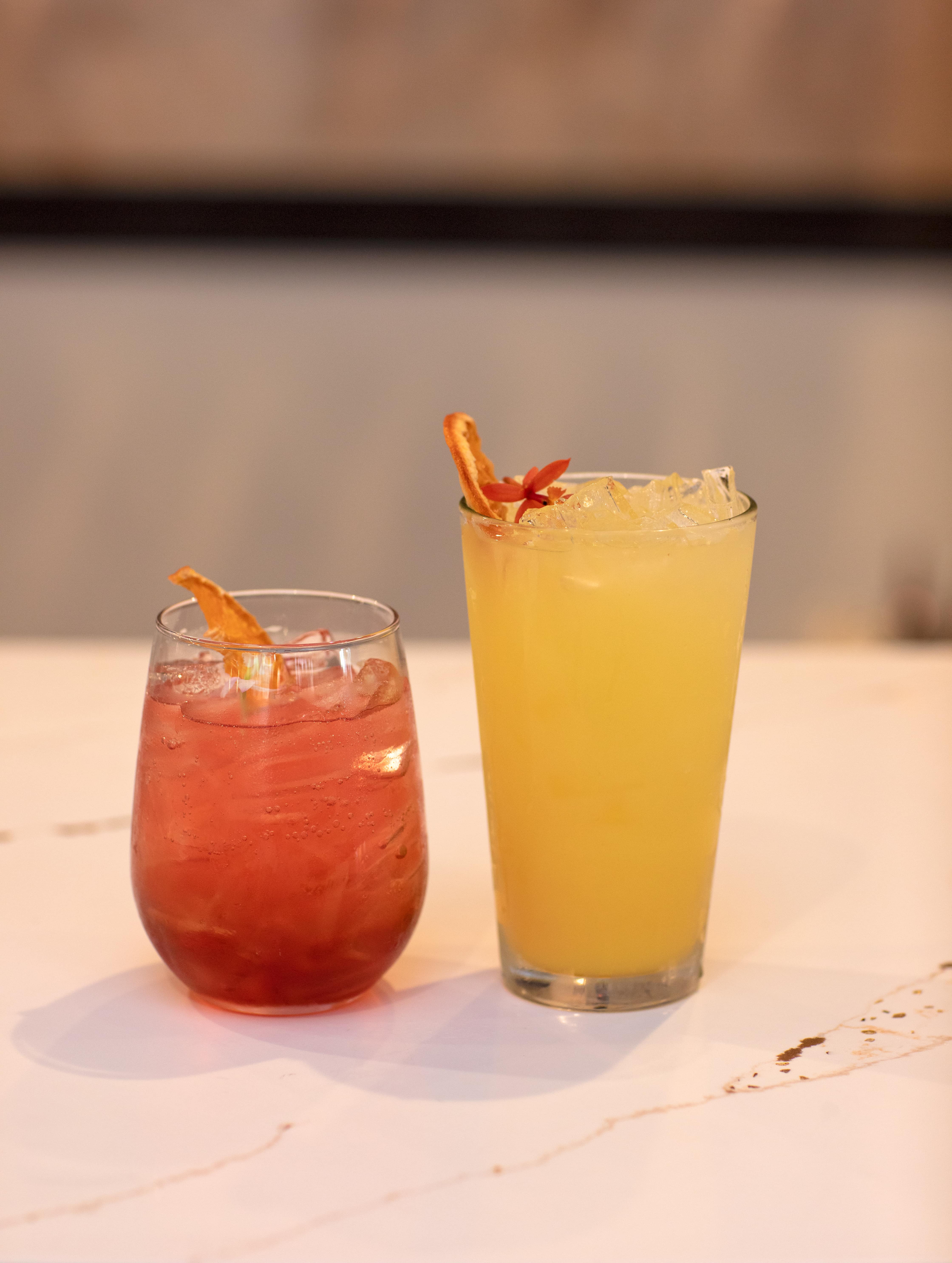 Tall orange cocktail with a dried citrus and edible flower