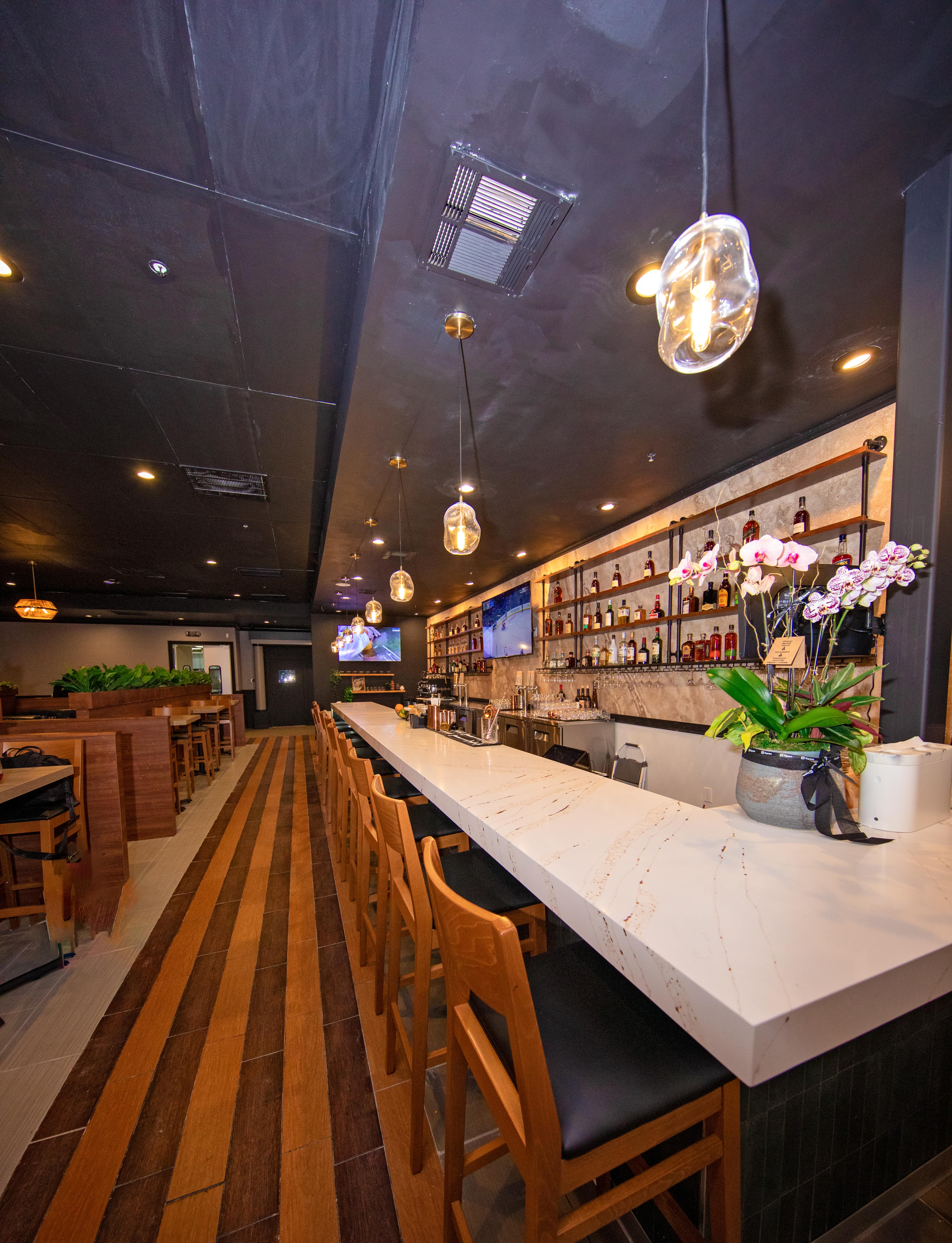 The long marble bar beneath pendant lights with a fresh orchid