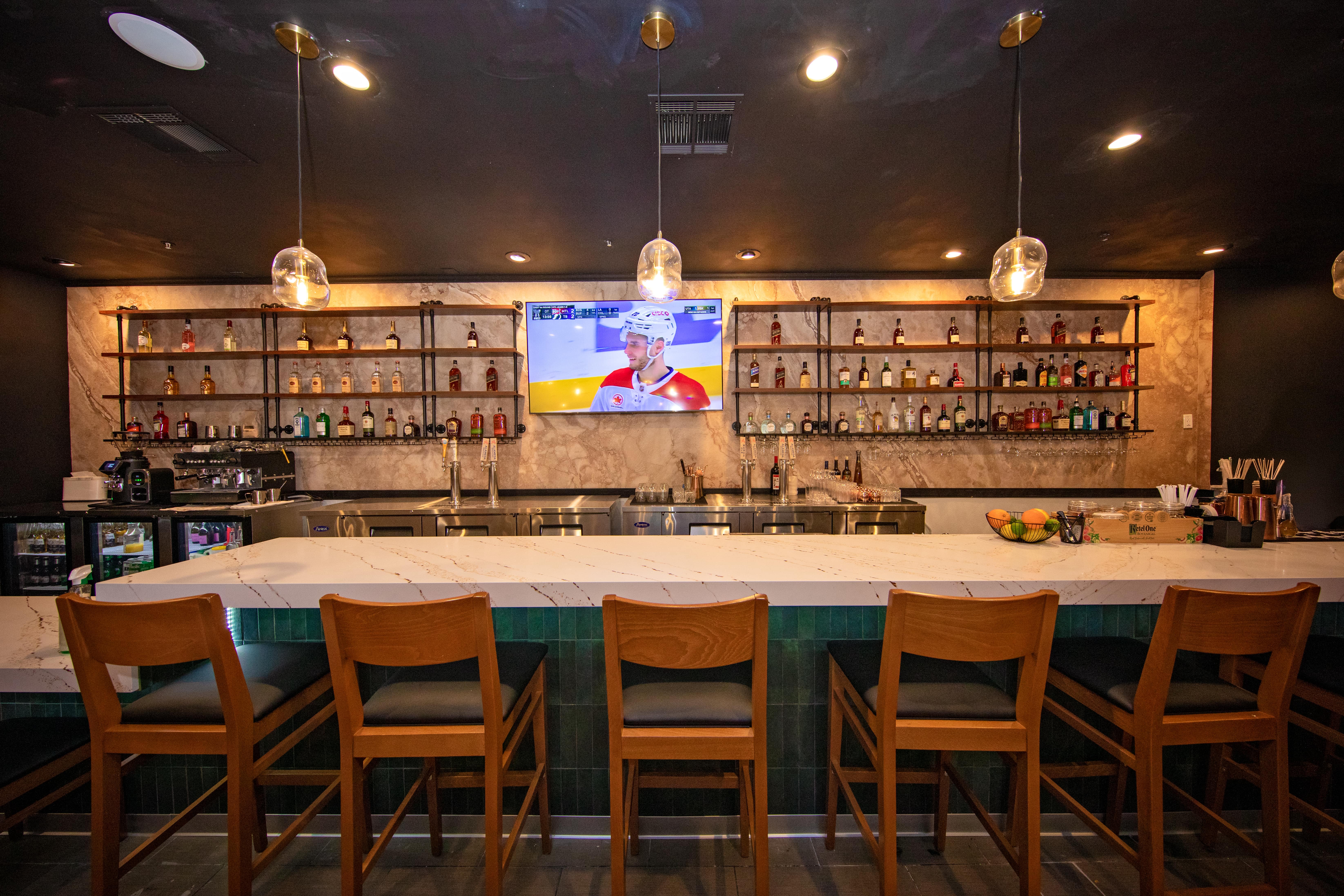The bar back with full bottle shelving and a sports TV