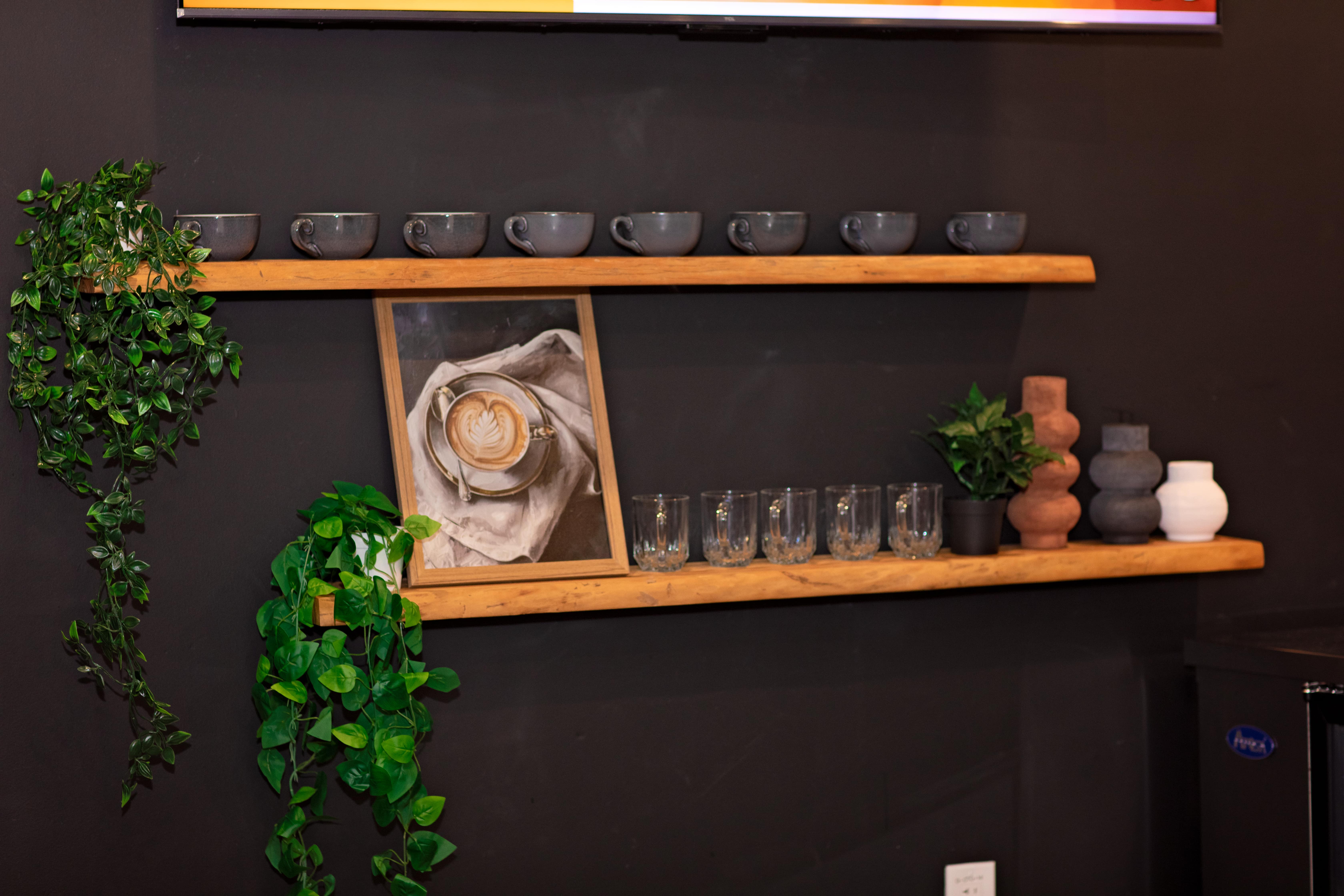 Floating coffee shelf with mugs, plants, and a framed latte art print